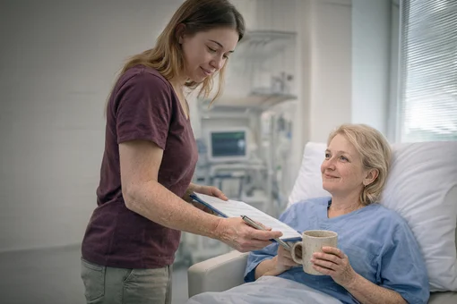 Physical therapy and rehabilitation exercise. A female physical therapist in a white uniform guiding a male patient through arm mobility exercises in a bright, modern therapy clinic.